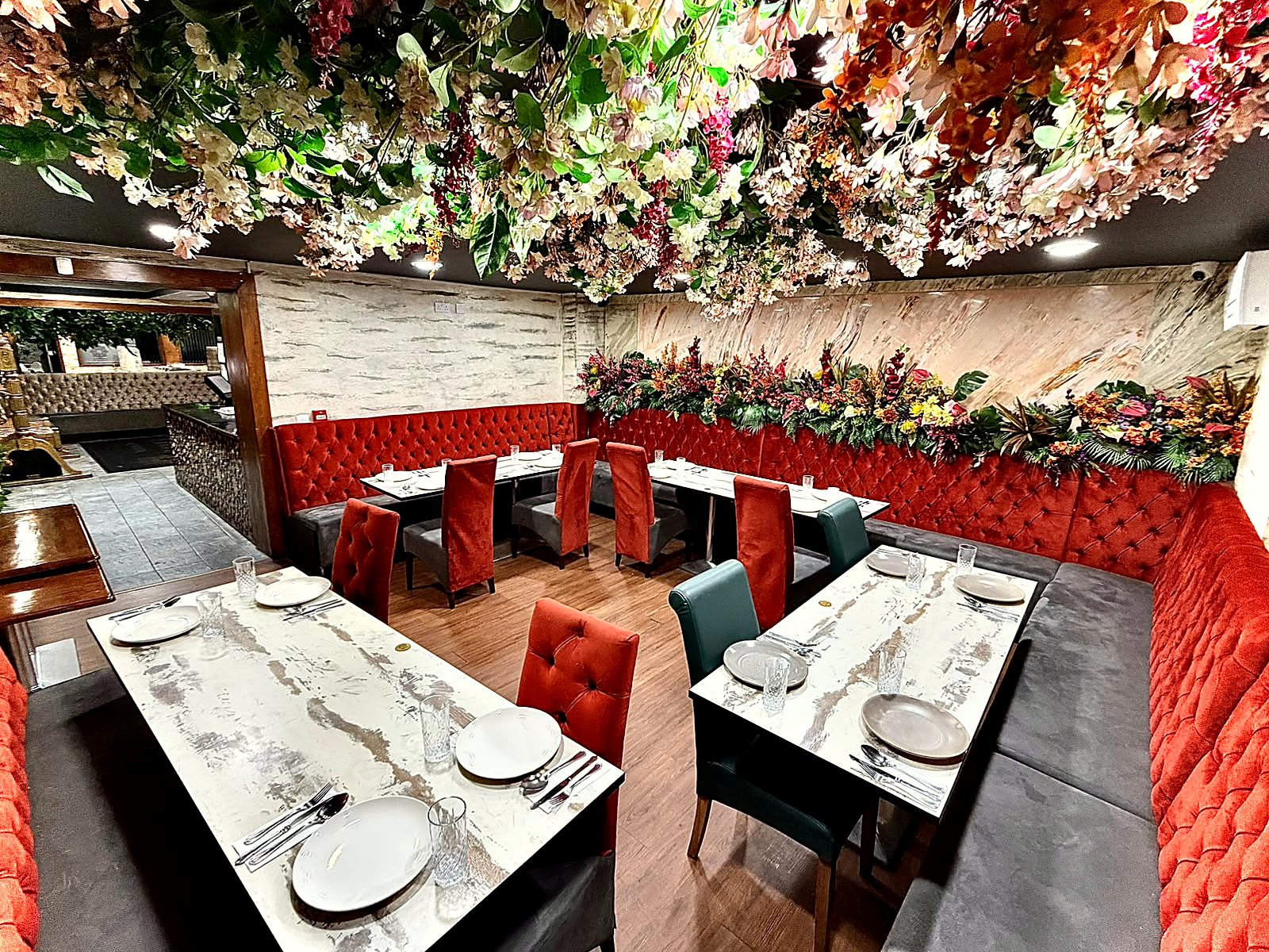 One of the private dining rooms at 3 Five 1, with red velvet booths, set tables and a ceiling of hanging flowers