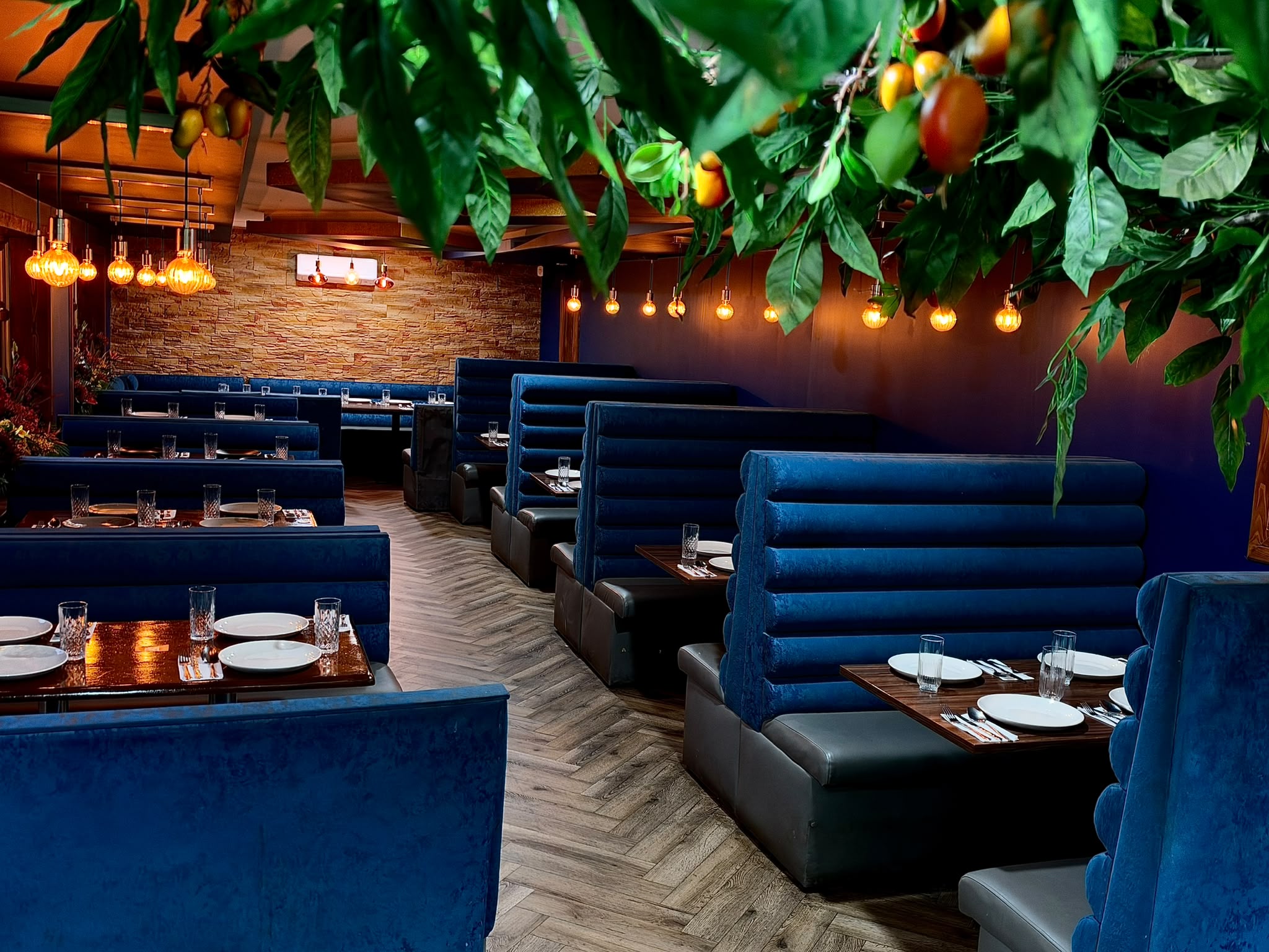 Blue velvet dining booths with hanging greenery and warm lighting