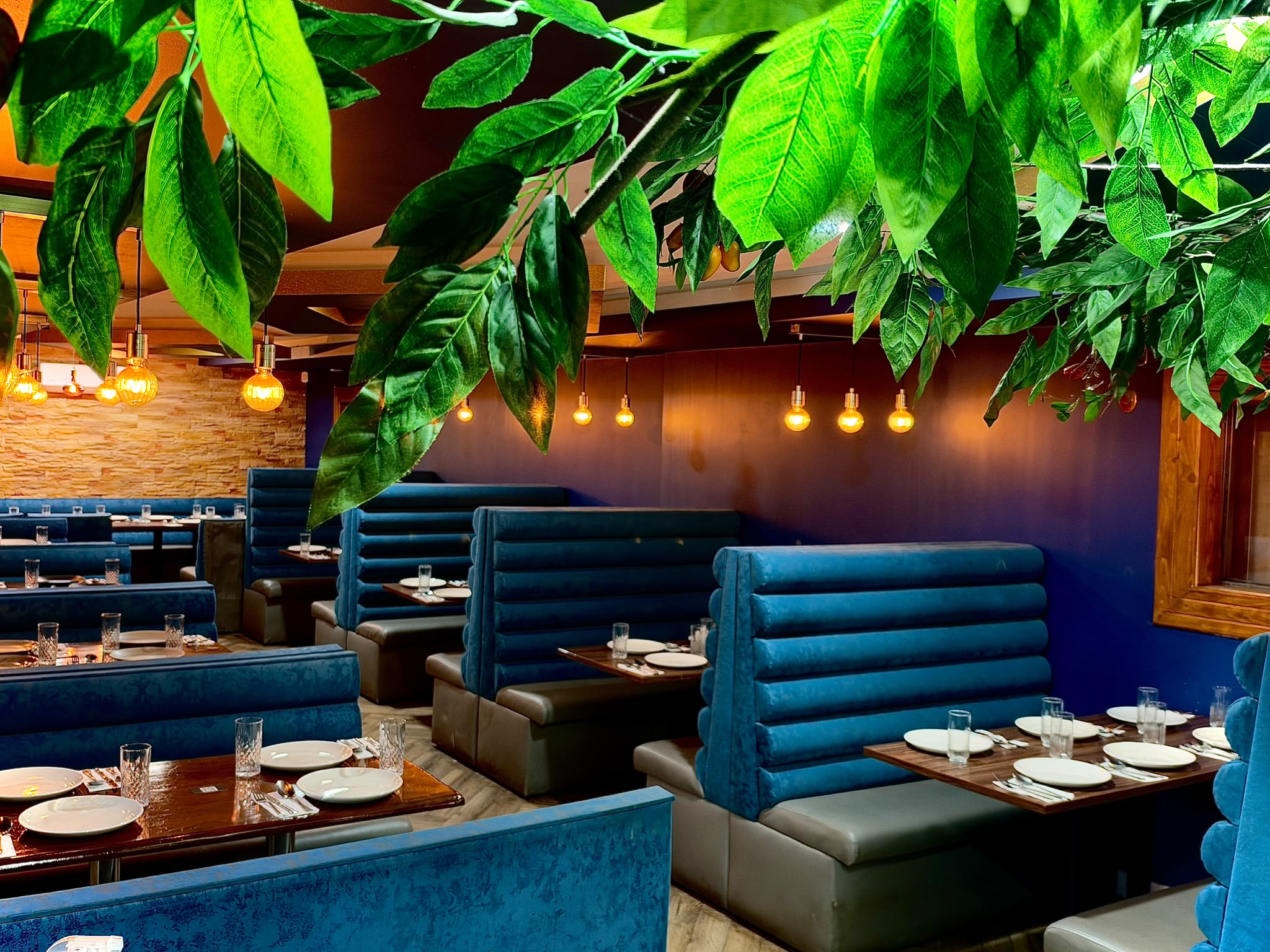 Blue velvet booths and lush greenery in the dining room